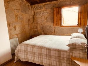 a bedroom with a bed in a stone wall at Refúgio da Póvoa Dão in Silgueiros