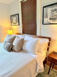 a bedroom with a bed with white sheets and a window at Couples Cottage with Hot Tub in Mathews