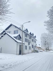 a snow covered street with a white house at M&M Marzeniowo in Chlebowo