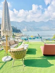 a patio with chairs and an umbrella and the water at DUBAI by luxury Atitlan in San Pedro La Laguna