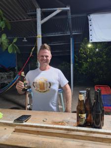 a man standing next to a table with bottles of beer at La Estancia in Lanquín