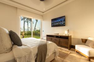 a bedroom with a bed and a tv and a chair at Exclusive Oceanfront Apartment Beach access in Acapulco