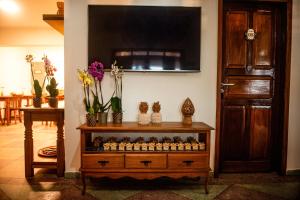 a room with a tv and a dresser with flowers on it at A Flor Pousada in Garanhuns