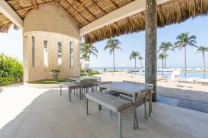 an outdoor patio with tables and chairs and the beach at Exclusive Oceanfront Apartment Beach access in Acapulco
