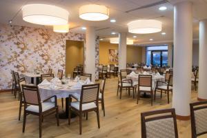 a dining room with tables and chairs and flowers at Domitys - Le Carillon d'or in Maubeuge