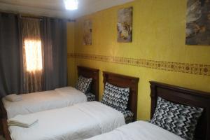 two beds in a room with yellow walls at Sun & Sea house in Agadir