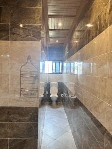 a bathroom with a toilet and a tiled wall at Résidence Prestige KGV Appt 303 in Douala +48 photos