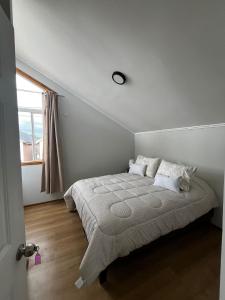 a white bedroom with a bed with a window at Casa Jesy in Frutillar