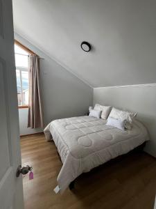 a white bedroom with a bed with pillows and a window at Casa Jesy in Frutillar