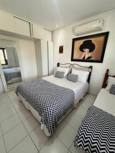 a bedroom with two beds and a painting on the wall at Espaço Ybirá in Marechal Deodoro +65 photos