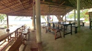 a group of wooden tables and benches in a building at La Ong Lay in Ko Phayam