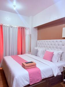 a bedroom with a large white bed with red curtains at Sunvida Tower Corner Suite Across SM Cebu in Cebu City