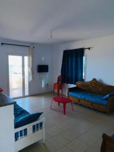 a living room with two beds and a red stool at V résidence in Ḩamādat al Kebalou