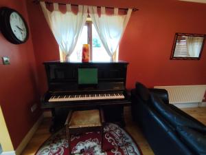 a piano in a room with a couch and a clock at An Tuar Ceatha in Castlebar +3 photos