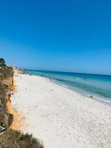 a beach with people on it and the ocean at V résidence in Ḩamādat al Kebalou
