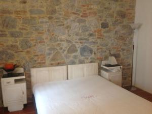 a bedroom with a white bed and a stone wall at Appartamento Al Tiglio in Lucca