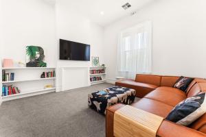a living room with a couch and a flat screen tv at Belle Escapes - The Light House in Glenelg