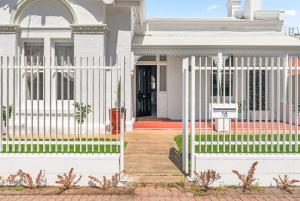 a white fence in front of a house at Belle Escapes - The Light House in Glenelg