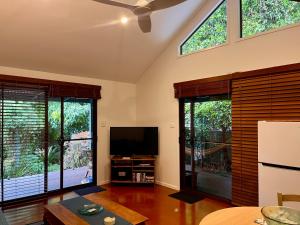 a living room with large windows and a flat screen tv at Byron Beach Cabin in Byron Bay