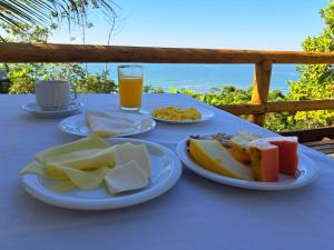 a table with plates of food and a glass of orange juice at Chale Tupi da Pedra in Trindade