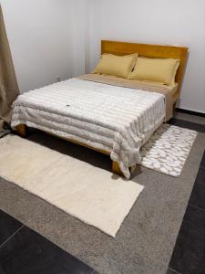 ein Schlafzimmer mit einem Bett und zwei Teppichen auf dem Boden in der Unterkunft Come chez soi in Abidjan