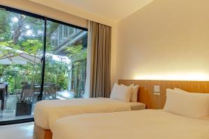 two beds in a room with a large window at kānusuba zamami in Zamami