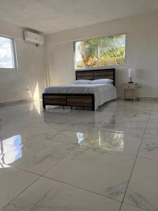 a bedroom with a bed and a large marble floor at VIP Hotel Haiti in Port-de-Paix