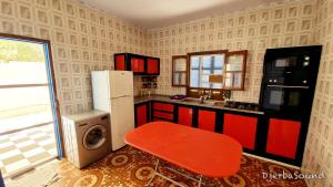a kitchen with a red stool and a refrigerator at Villas calme et sans vis-à-vis proche de la plage Tezdaine in Midoun