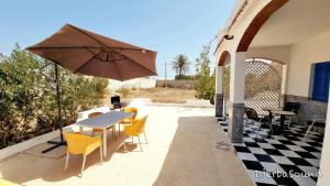 a table and chairs and an umbrella on a patio at Villas calme et sans vis-à-vis proche de la plage Tezdaine in Midoun