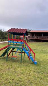 a colorful play structure in a field of grass at Cabanas Vista da Pedra in Grão Pará +9 photos