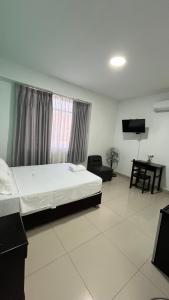 a bedroom with a bed and a tv in a room at Hostal Bali - Talara in Talara