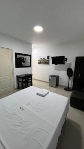 a bedroom with a white bed and a couch at Hostal Bali - Talara in Talara