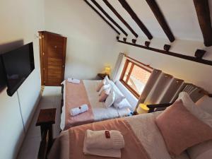a room with two beds and a tv and a window at Casa Hotel La Morada in Villa de Leyva