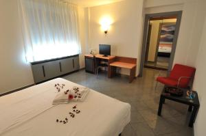 a room with a bed and a desk with a red chair at Hotel Bahnhof Haus in Chiasso