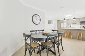 a dining room table with chairs and a clock on the wall at Prime on Piper in Bathurst