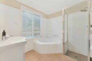 a white bathroom with a shower and a toilet and a sink at Prime on Piper in Bathurst
