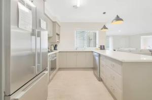 a white kitchen with white cabinets and a refrigerator at Prime on Piper in Bathurst +10 photos