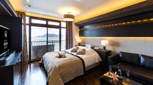 a bedroom with a large bed and a balcony at HOTEL MYTH-Resort -ホテル マイス リゾート- adult only in Nagato