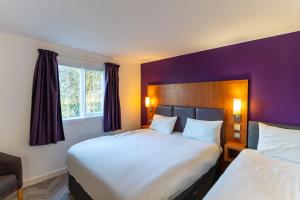 a hotel room with two beds and a purple wall at Mundy Arms Hotel Derby in Derby