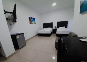 a room with two beds and a table in it at Hostal Bali - Talara in Talara +5 photos