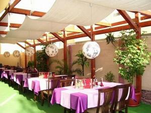 ein Esszimmer mit Tischen, Stühlen und Uhren in der Unterkunft Hotel Amfibia in Primorsko