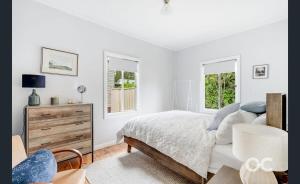 a white bedroom with a bed and two windows at Wollemi Cottage Orange in Orange