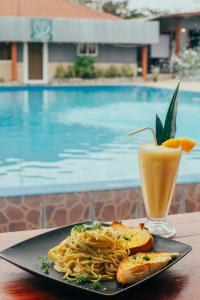 a plate of pasta and a drink next to a pool at Isabella Hostel and Pool in Alto Boquete
