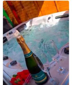 a bottle of champagne in a hot tub with glasses at Eden hibiscus in Petit-Canal