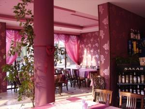 a restaurant with pink walls and tables and chairs at Hotel Amfibia in Primorsko