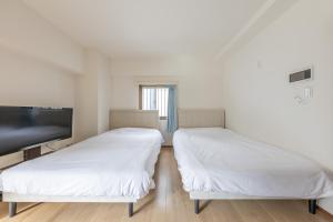 two beds in a room with a flat screen tv at Jintai House201 in Fukuoka