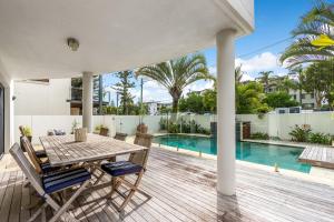 a patio with a table and chairs and a swimming pool at Luxurious Beachside Oasis with Ocean Views in Gold Coast