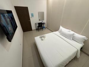 a bed with white sheets and pillows in a room at One Point Hotel @ Airport (Kuching) in Kuching