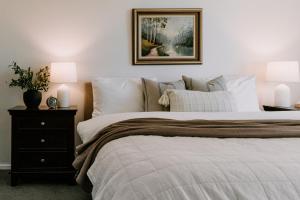 a bedroom with a bed with two lamps and a picture on the wall at Old Maffra Cottage in Maffra