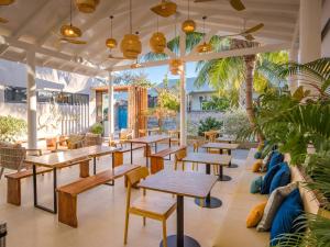 a restaurant with tables and benches and palm trees at Biosphere Beach in Dharavandhoo